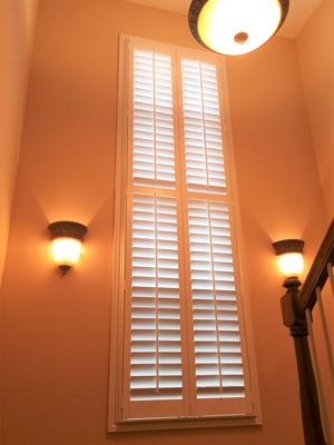 White plantation shutters in brightly lit stairwell.